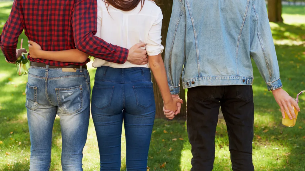 a man and a woman with their arms around each other while the woman hold's another man's hand
