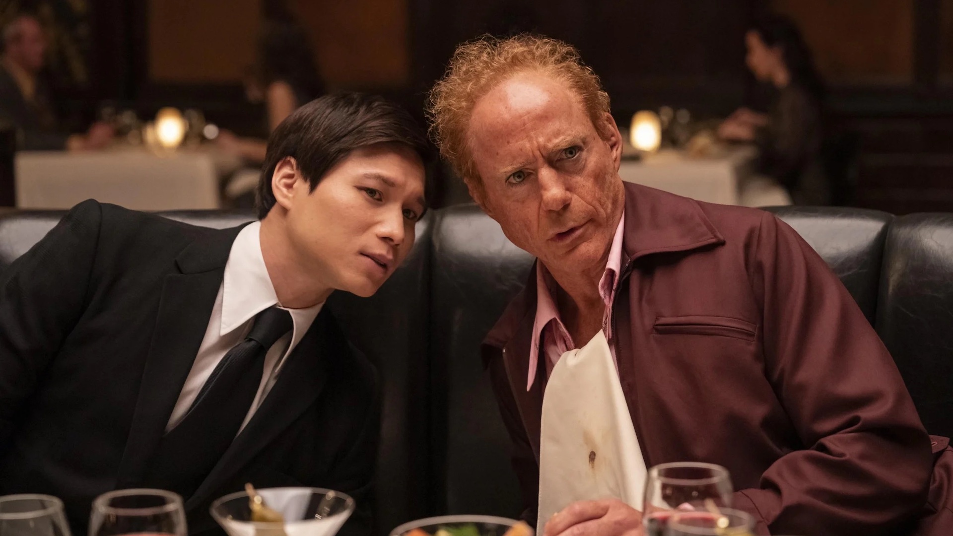 Hoa Xuande and Robert Downey Jr. are pictured talking in a restaurant in a still from HBO show The Sympathizer