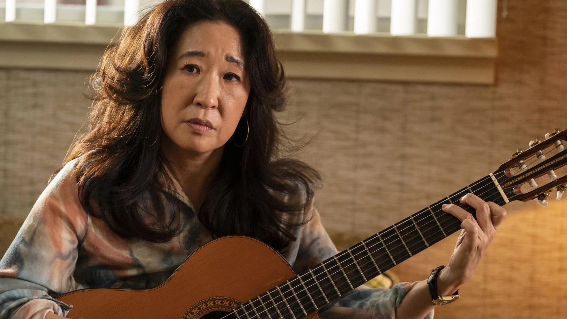 Sandra Oh is pictured holding a guitar in a still from HBO show The Sympathizer